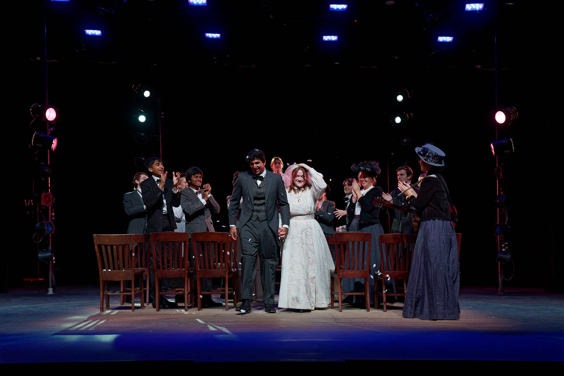 A man and women walk down the aisle in wedding clothes as a crowd celebrates on both sides