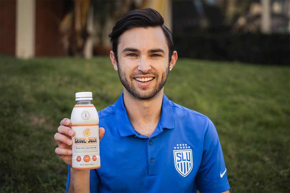 Luis Manta holds a bottle of Seoul Juice while facing the camera