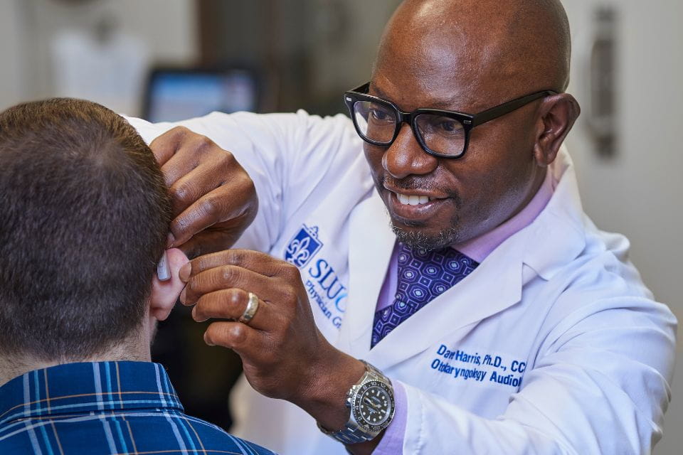 A SLUCare audiologist examines a patient's ear.