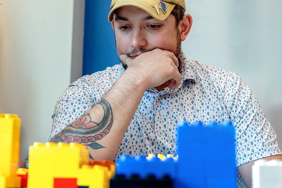 young man with ballcap works with large Lego blocks