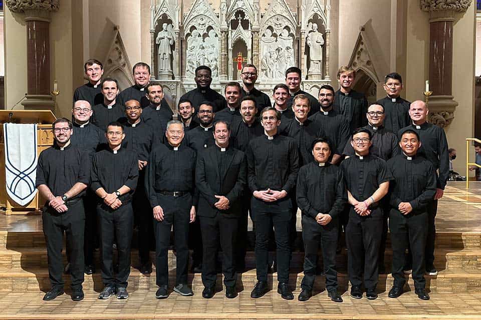 A group of Jesuit scholastics in front of the alter at St. Francis Xavier College Church