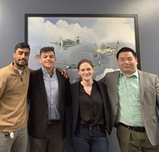 Team posed for a group shot in front of a picture of planes