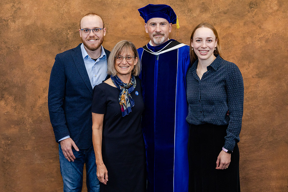 A formal photo of the Feser family, including SLU President Ed Feser in academic regalia, his wife, son and daughter